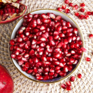 A white bowl is filled with pomegranate arils.