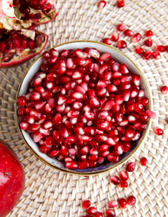 A white bowl is filled with pomegranate arils.