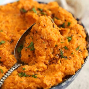 Bowl of mashed sweet potatoes with serving spoon