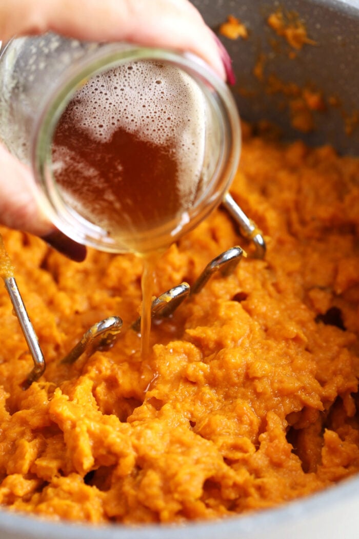 Pouring brown butter into mashed sweet potatoes