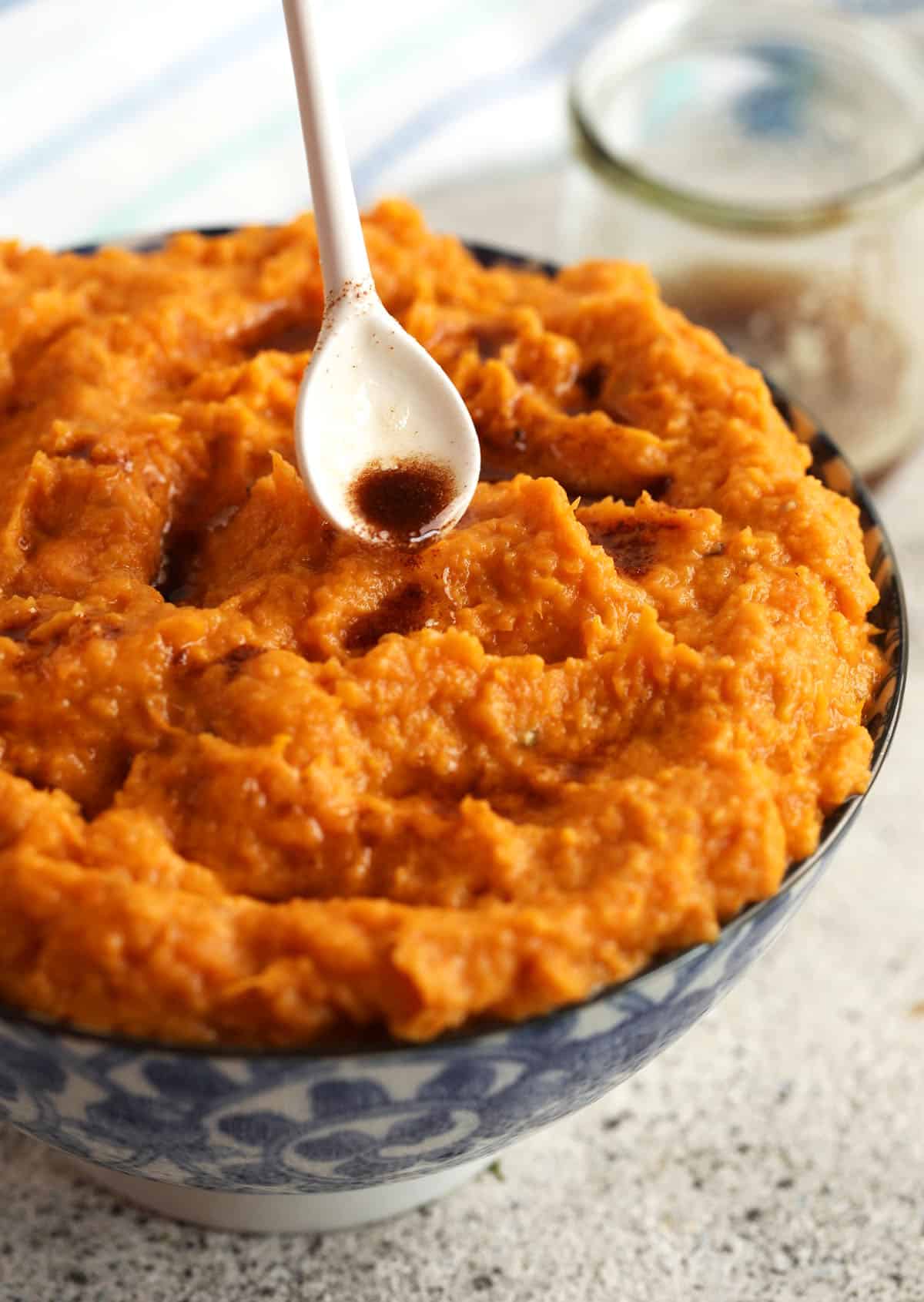 Drizzling brown butter into bowl of mashed sweet potatoes