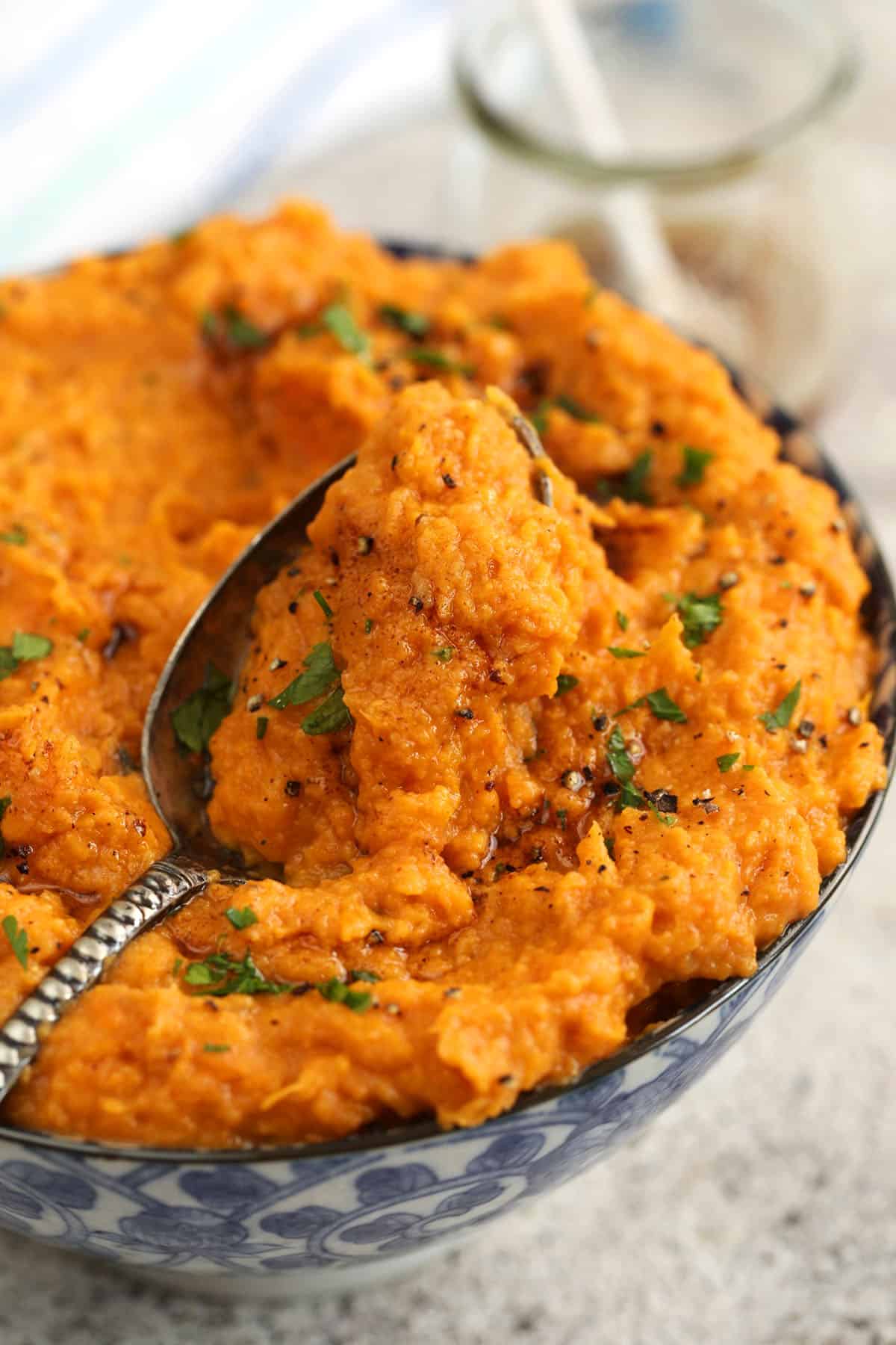 Bowl of mashed sweet potatoes with serving spoon