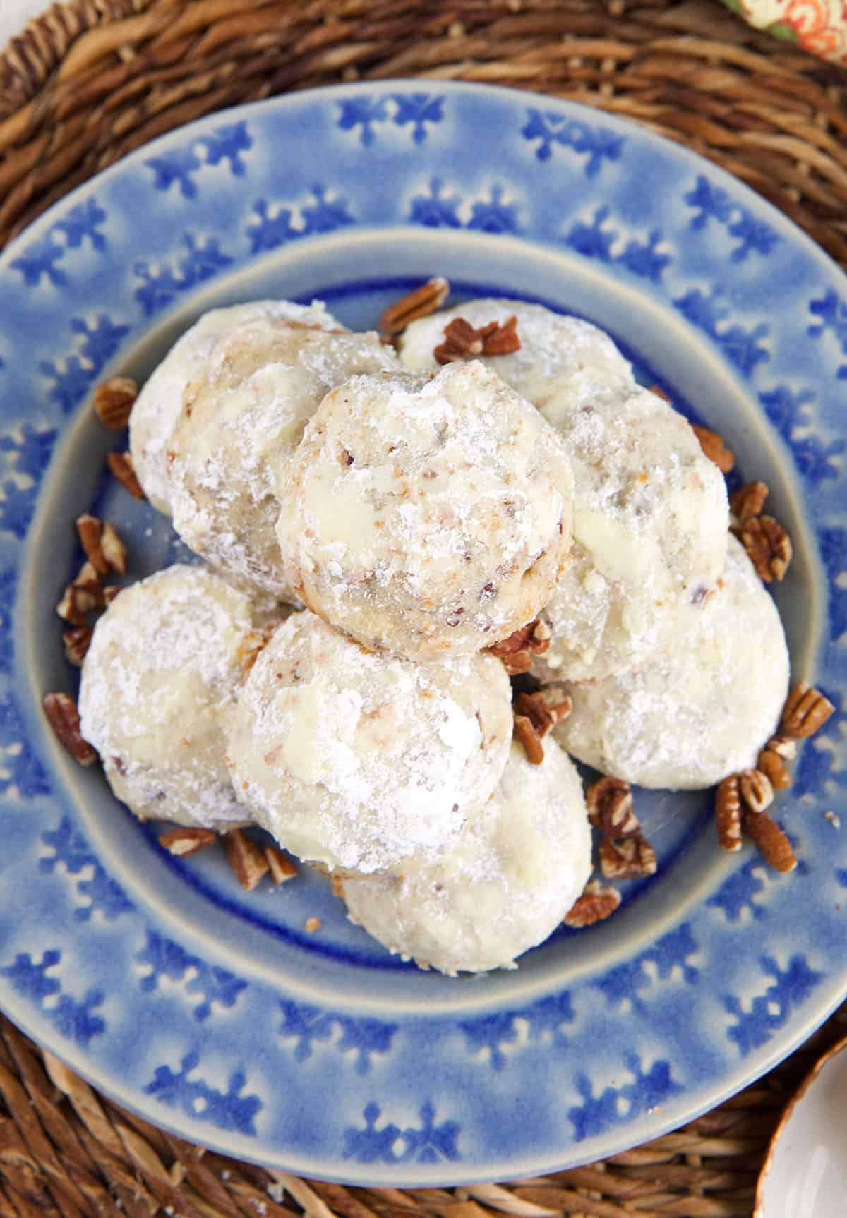 A plate is topped with pecans and Mexican wedding cookies. 