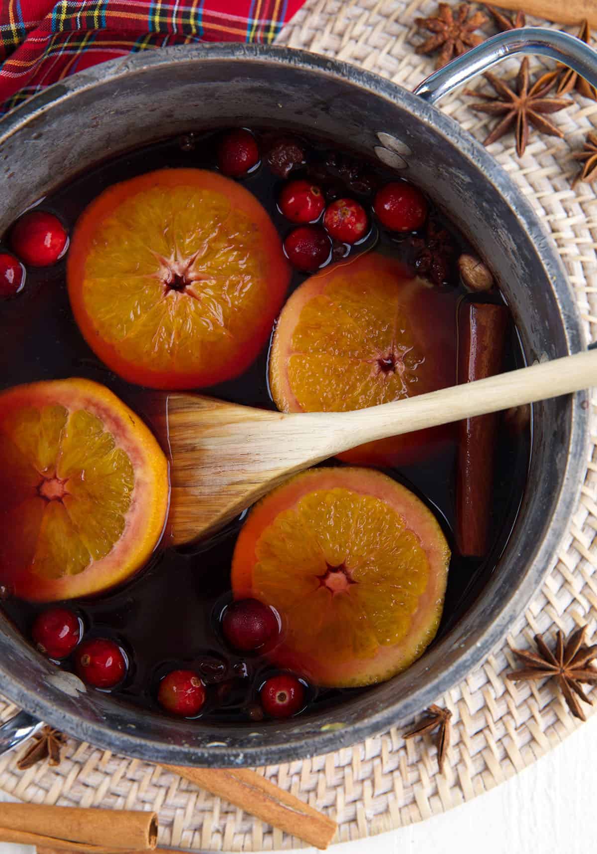 A pot is filled with mulled wine ingredients simmering together. 