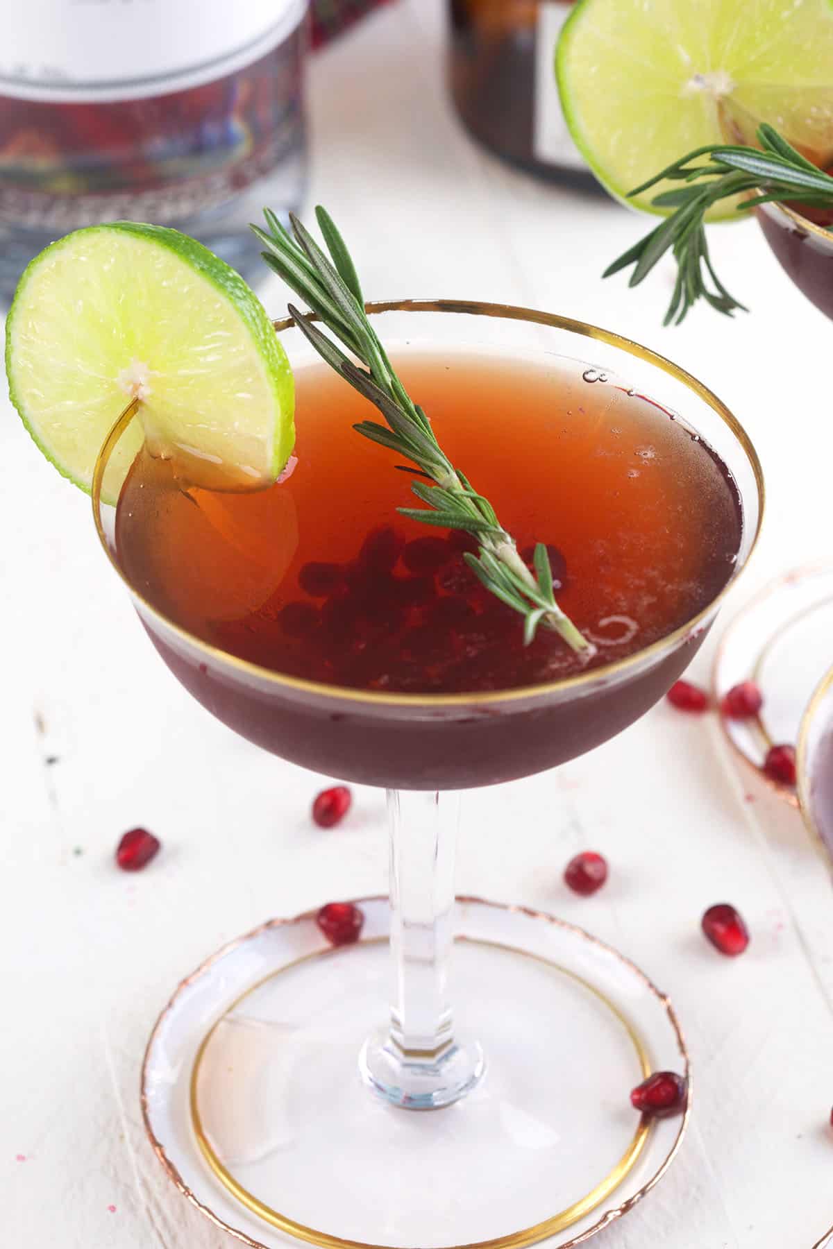 Rosemary, pomegranate arils and a lime wedge garnish a glass. 
