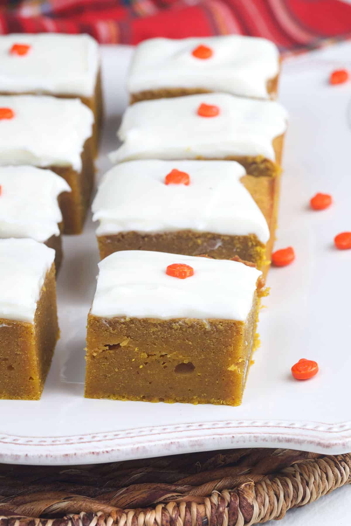 A batch of frosted pumpkin bars is sliced and presented on a white serving plate. 