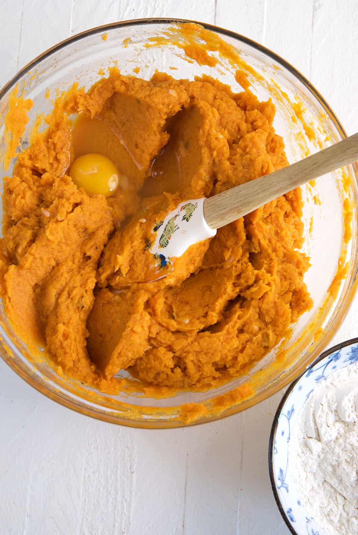 Pumpkin batter is being mixed in a glass bowl.