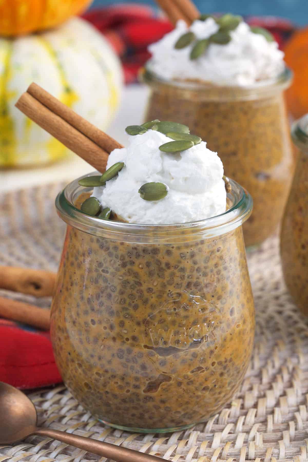 A glass jar filled with chia pudding is topped with whipped cream. 
