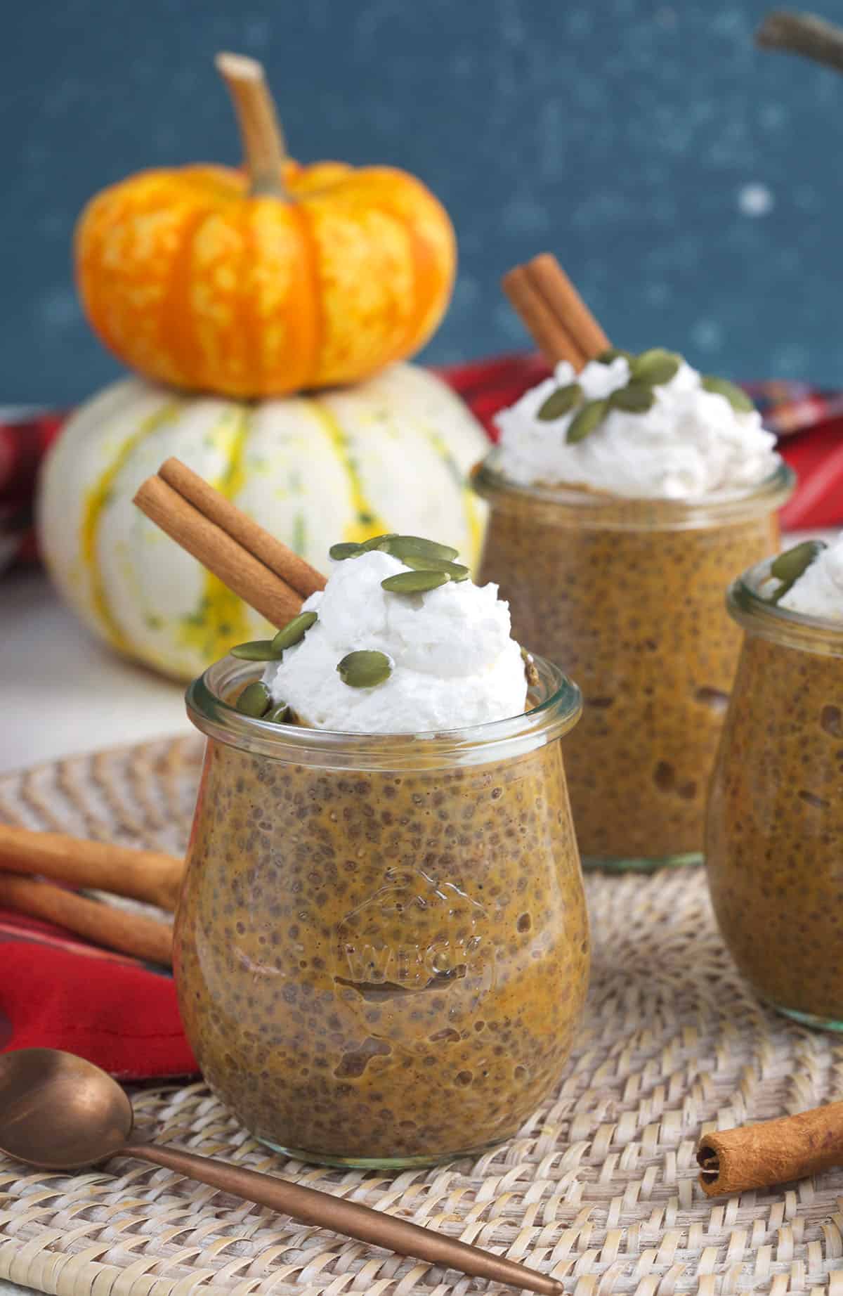 Pumpkins are stacked behind chia pudding.