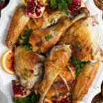 A white serving platter is topped with statchcock turkey.