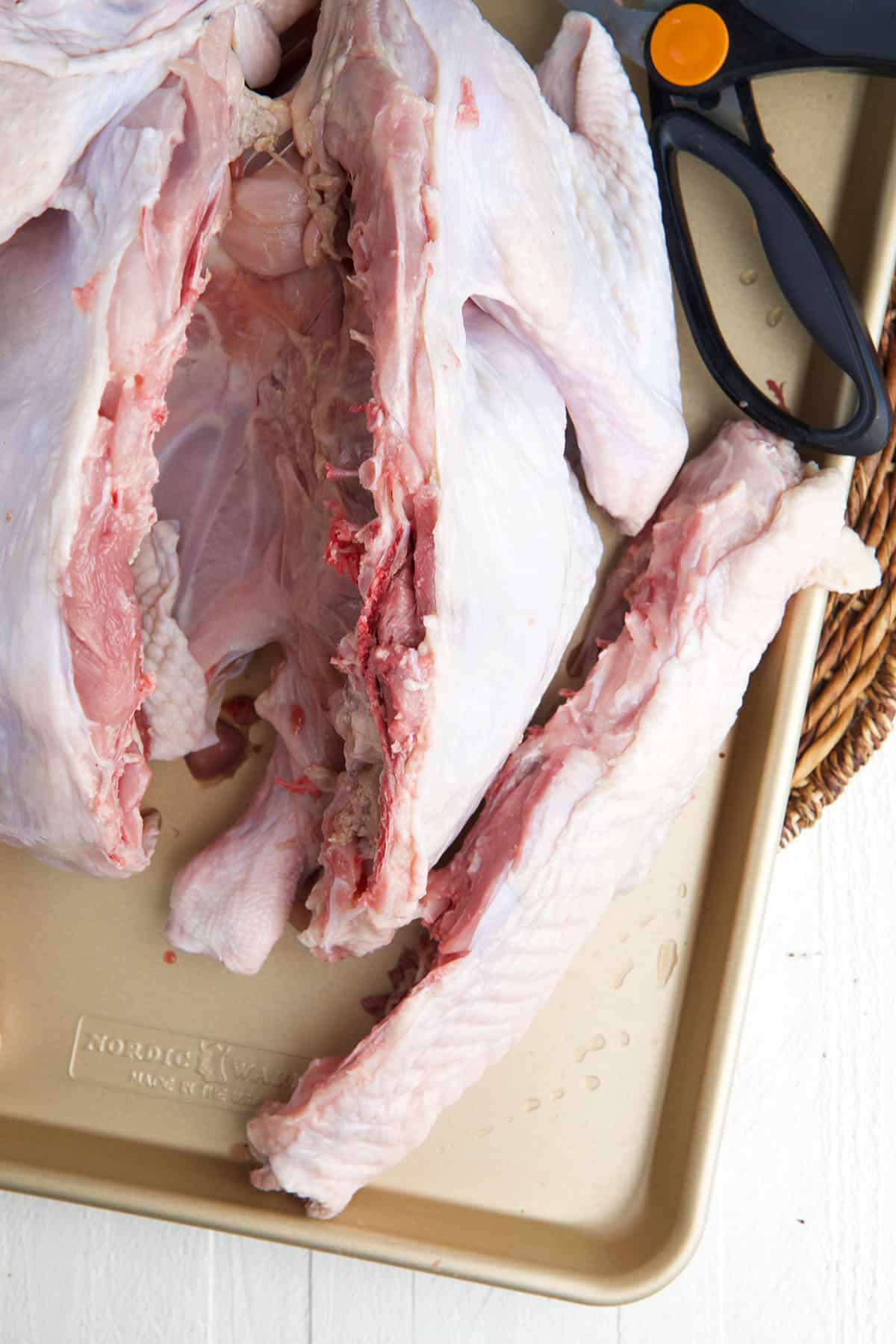 The backbone of a raw turkey has been removed. 