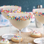 Several full martini glasses are placed next to each other.