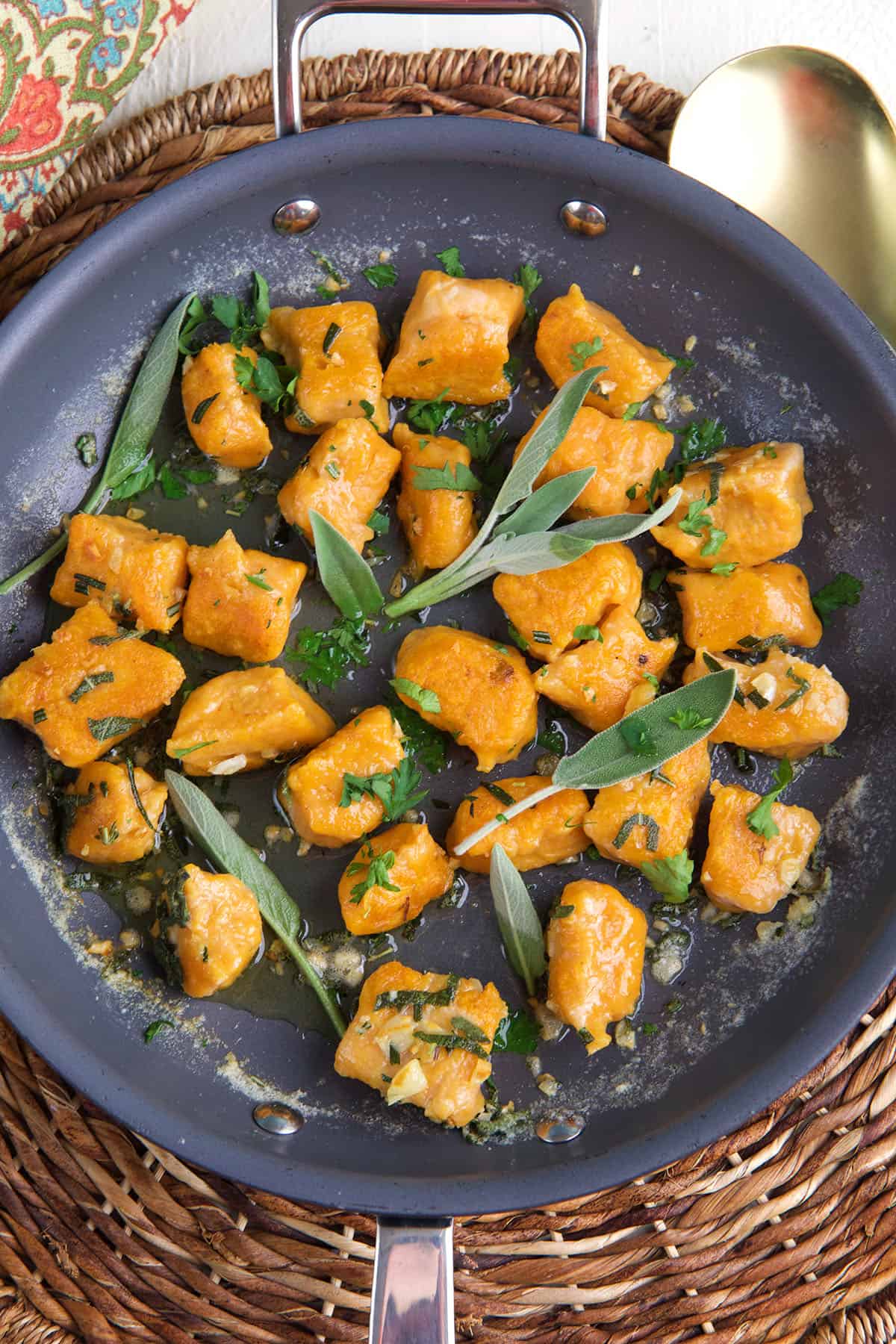 Sweet potato gnocchi and herbs are in a skillet. 