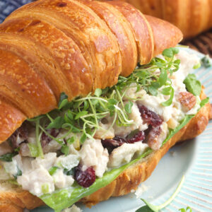 A croissant has been turned into a sandwich with microgreens and turkey salad.