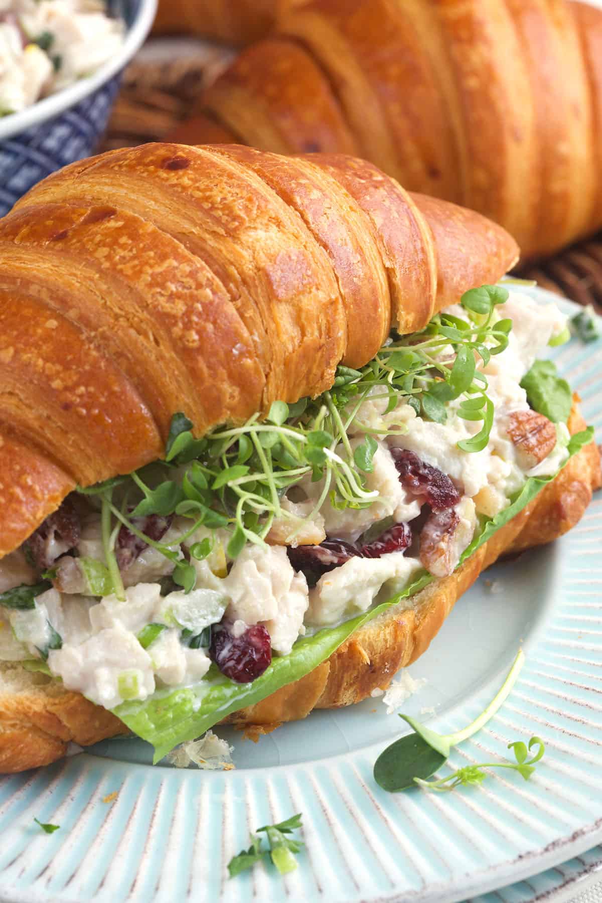 A croissant has been turned into a sandwich with microgreens and turkey salad. 