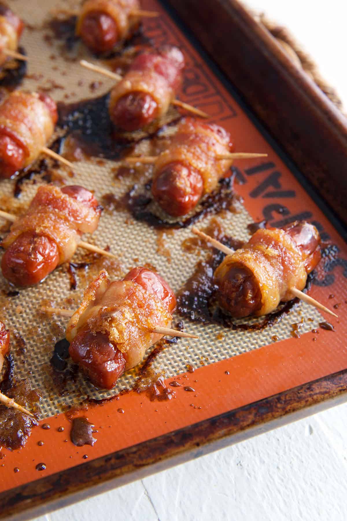 Baked little smokies with bacon are placed on a baking sheet. 