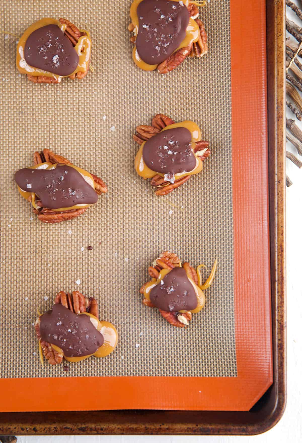 A small batch of turtle candies are placed on a siplat baking sheet. 