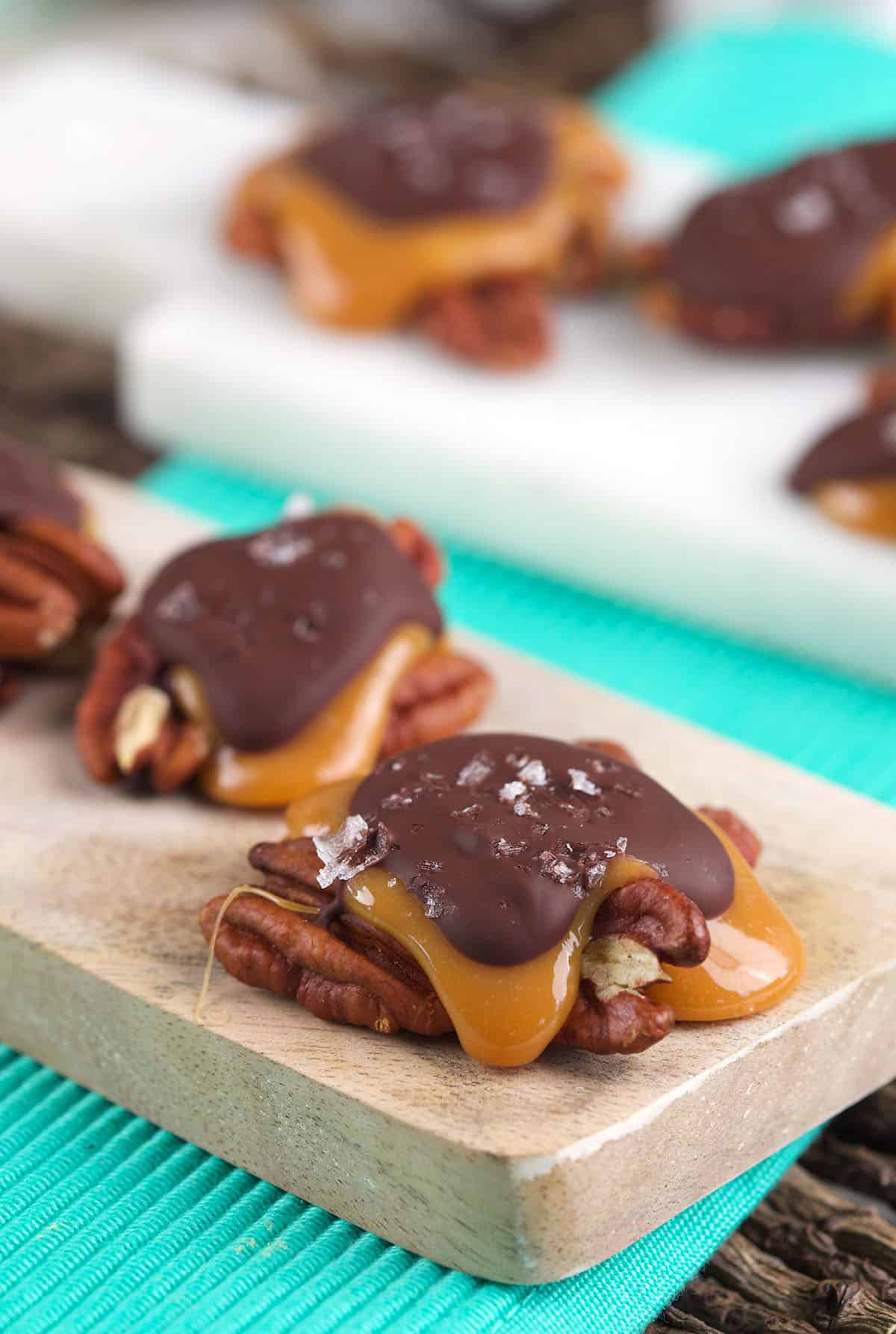 Several chocolate turtle candies are placed on a serving plate. 