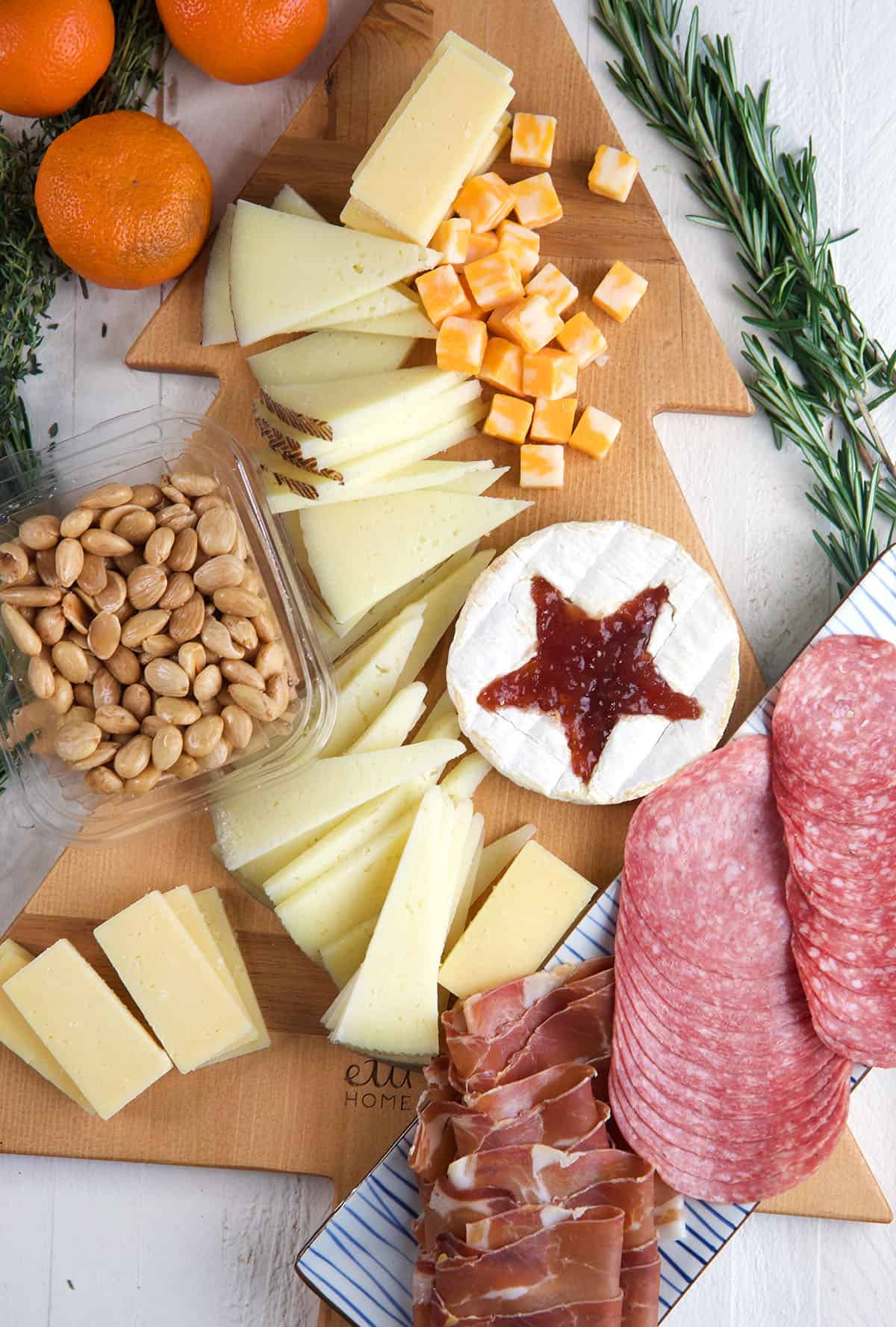 The ingredients for Christmas charcuterie are placed on a wooden tree shaped board. 