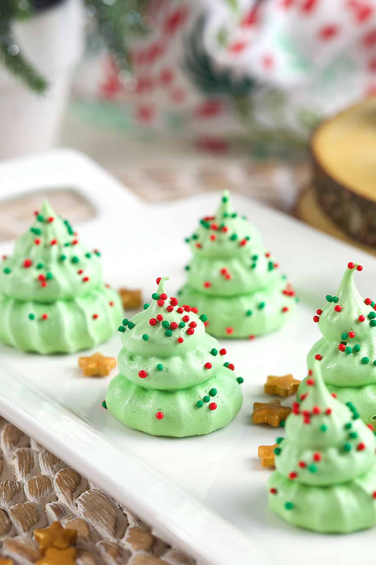 Several Christmas tree cookies are spread out on a white plate. 