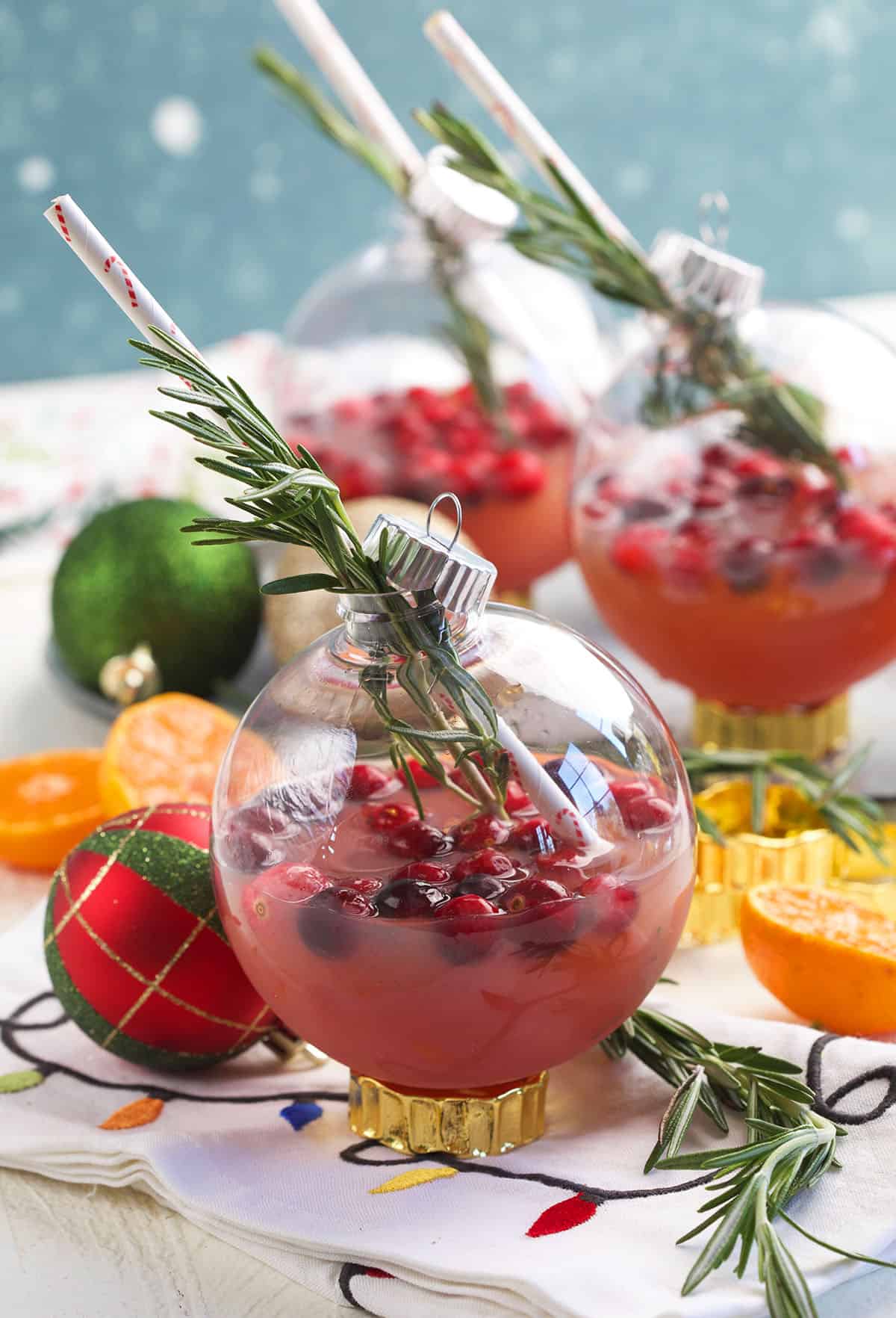 A Christmas ornament cocktail is garnished with rosemary. 