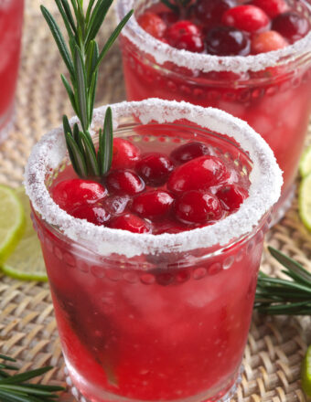 A cranberry margarita is garnished with berries and rosemary.