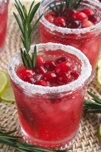 A cranberry margarita is garnished with berries and rosemary.