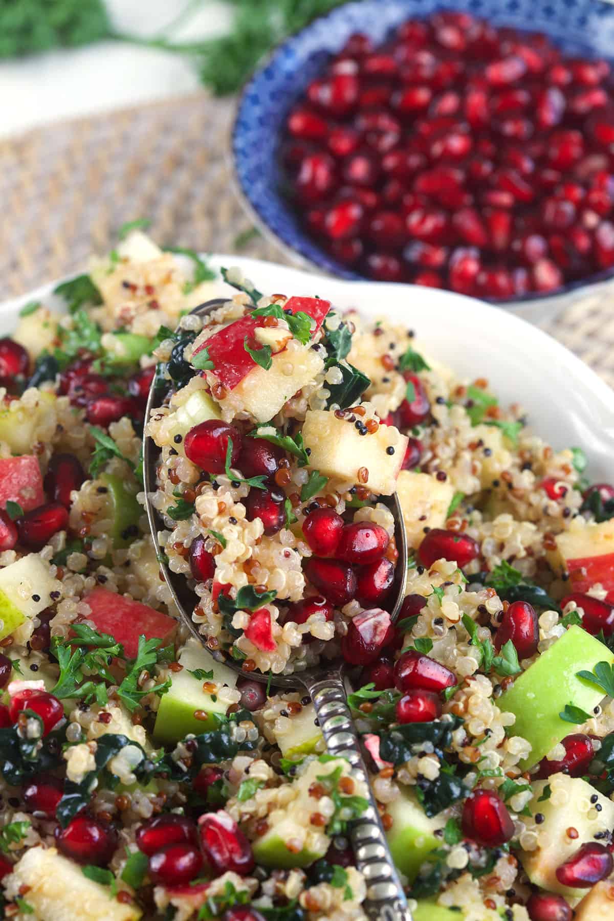 A serving spoon is holding a small portion of quinoa salad. 