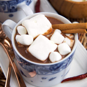 Marshmallows and a cinnamon stick garnish a cup of Mexican hot chocolate.