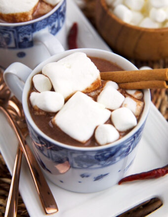 Marshmallows and a cinnamon stick garnish a cup of Mexican hot chocolate.
