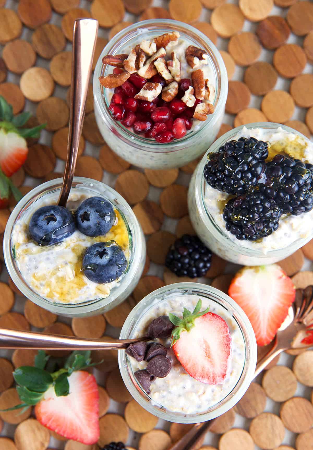 Four servings of overnight oats are garnished with berries. 