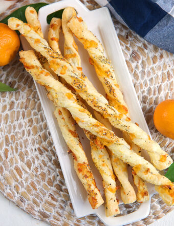 A batch of cheese straws are placed on a white serving plate.