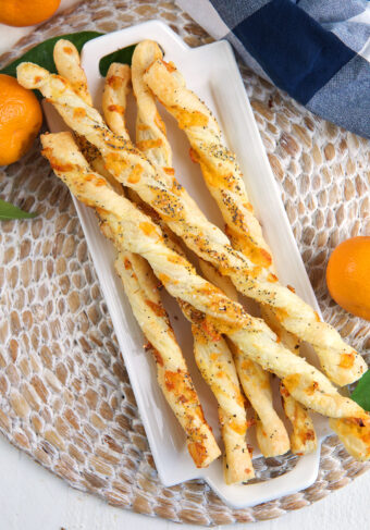 A batch of cheese straws are placed on a white serving plate.