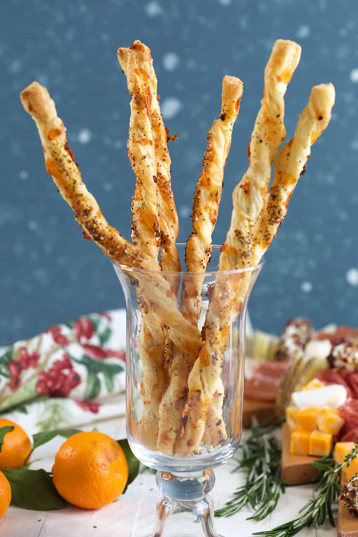 A glass jar is filled with puff pastry cheese straws. 