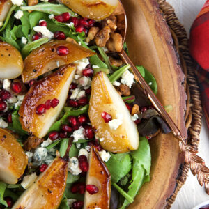 Roasted pear Salad in a wood bowl with a copper spoon for serving.