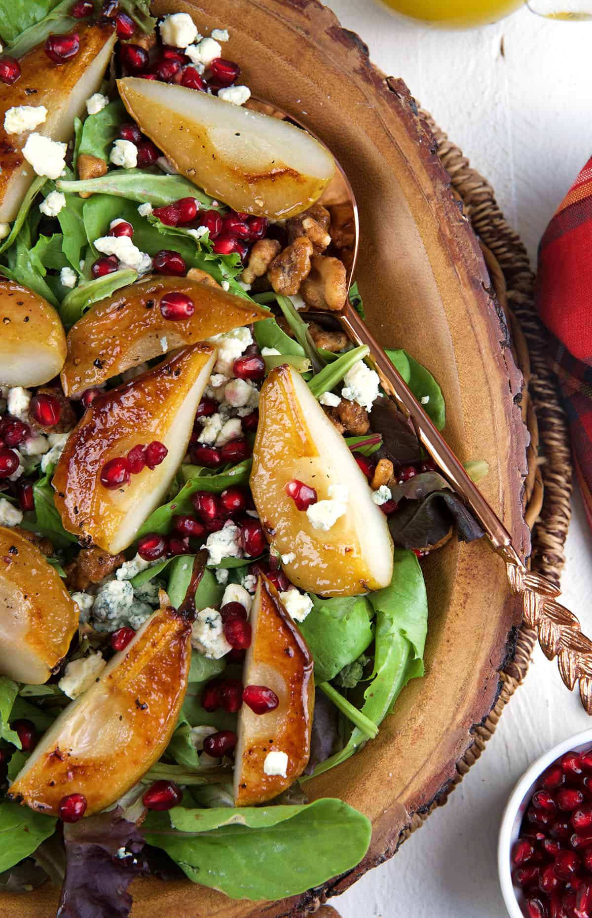 Roasted pear Salad in a wood bowl with a copper spoon for serving.