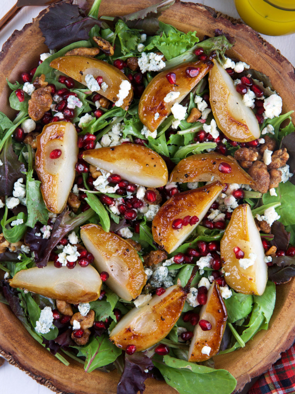 Roasted pear Salad in a live edge wood bowl with gorgonzola and pomegranate seeds sprinkles on top.