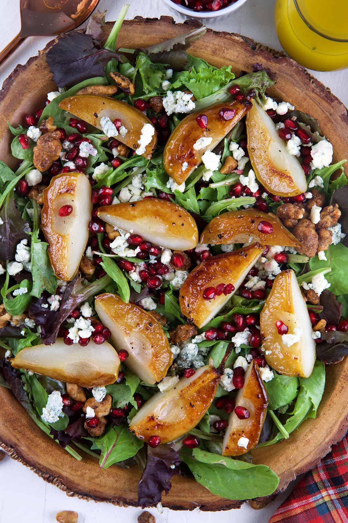 Roasted pear Salad in a live edge wood bowl with gorgonzola and pomegranate seeds sprinkles on top.