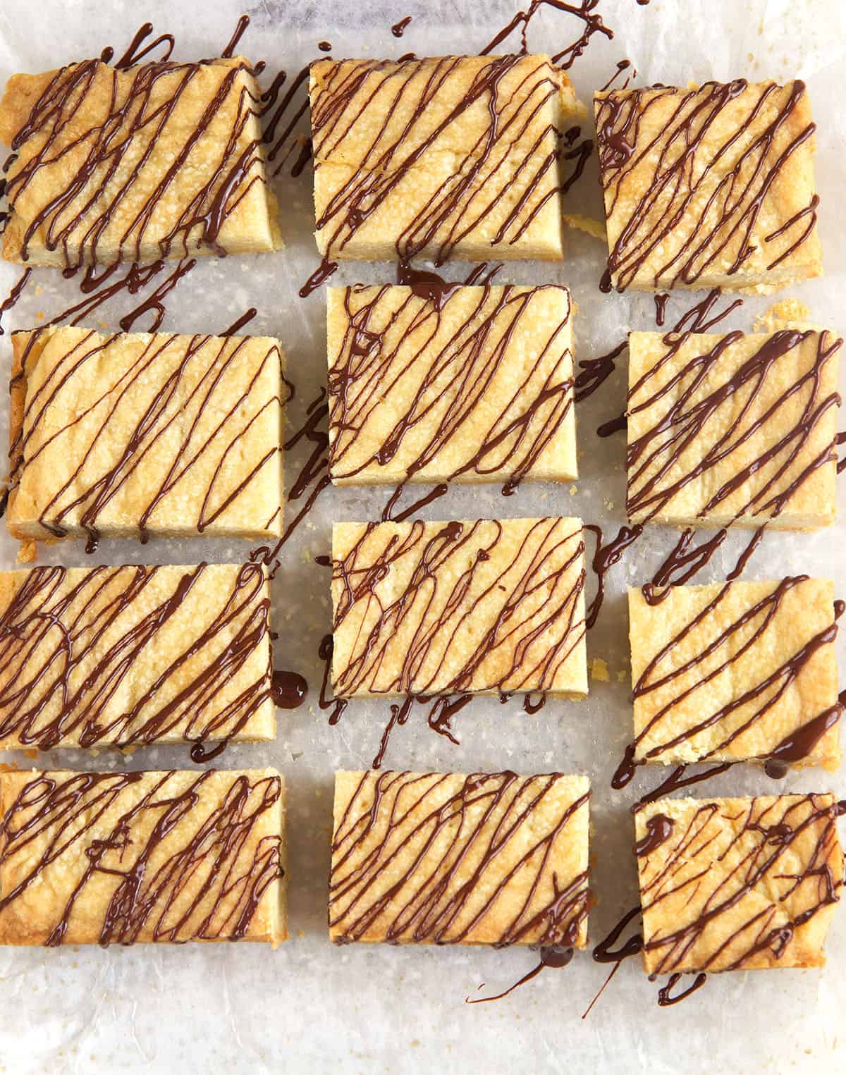 A batch of shortbread cookies are presented on a sheet of parchment paper. 