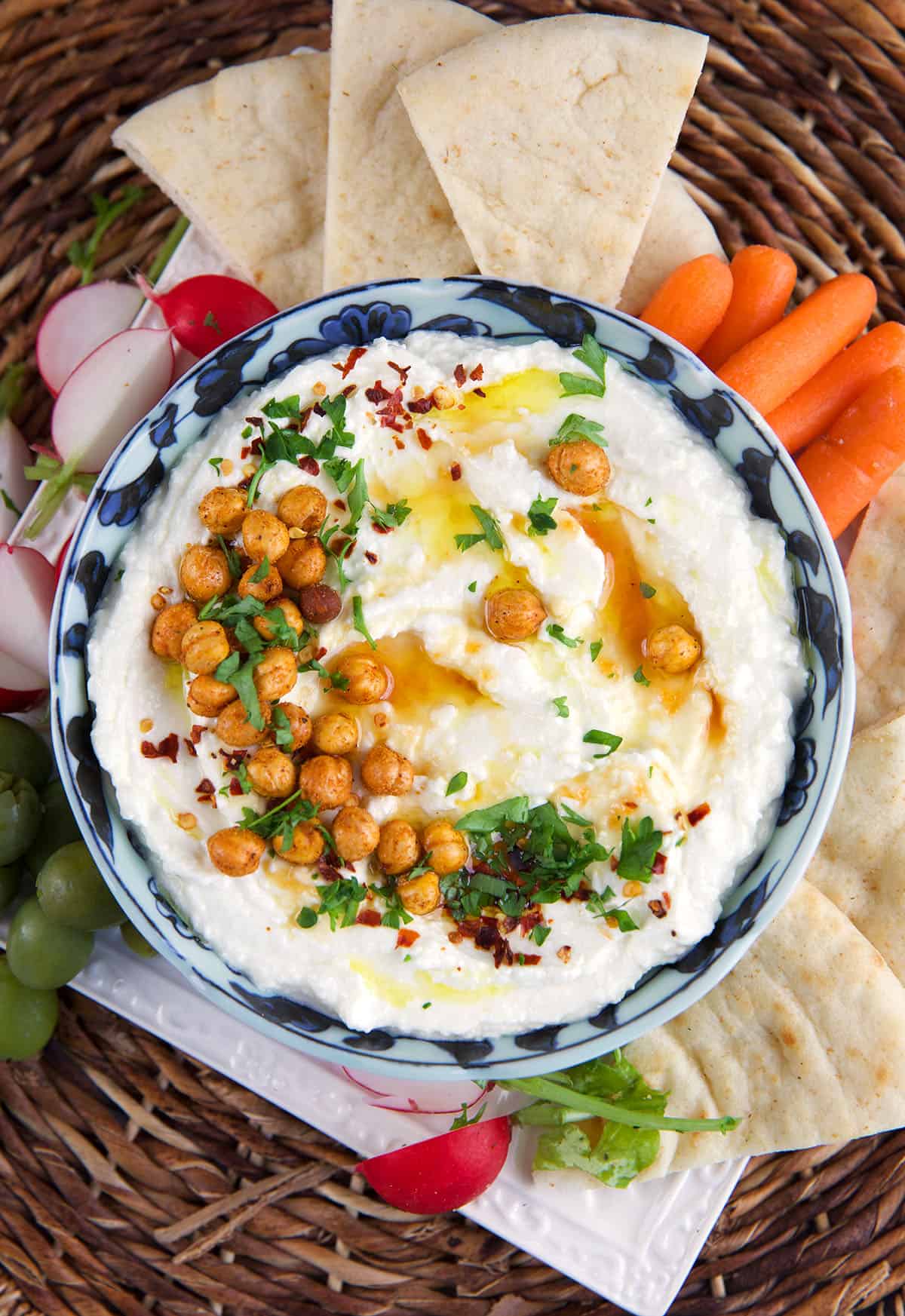 A bowl of whipped feta dip is topped with chickpeas and herbs. 