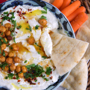 A single piece of pita is being dipped into feta dip.