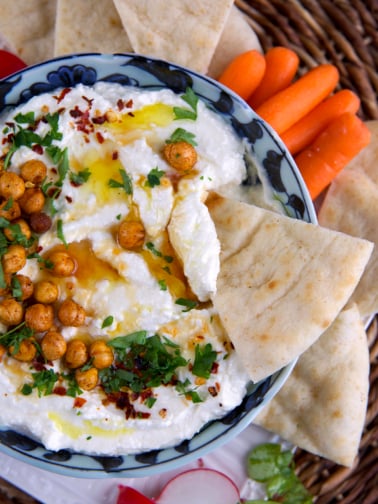 A single piece of pita is being dipped into feta dip.