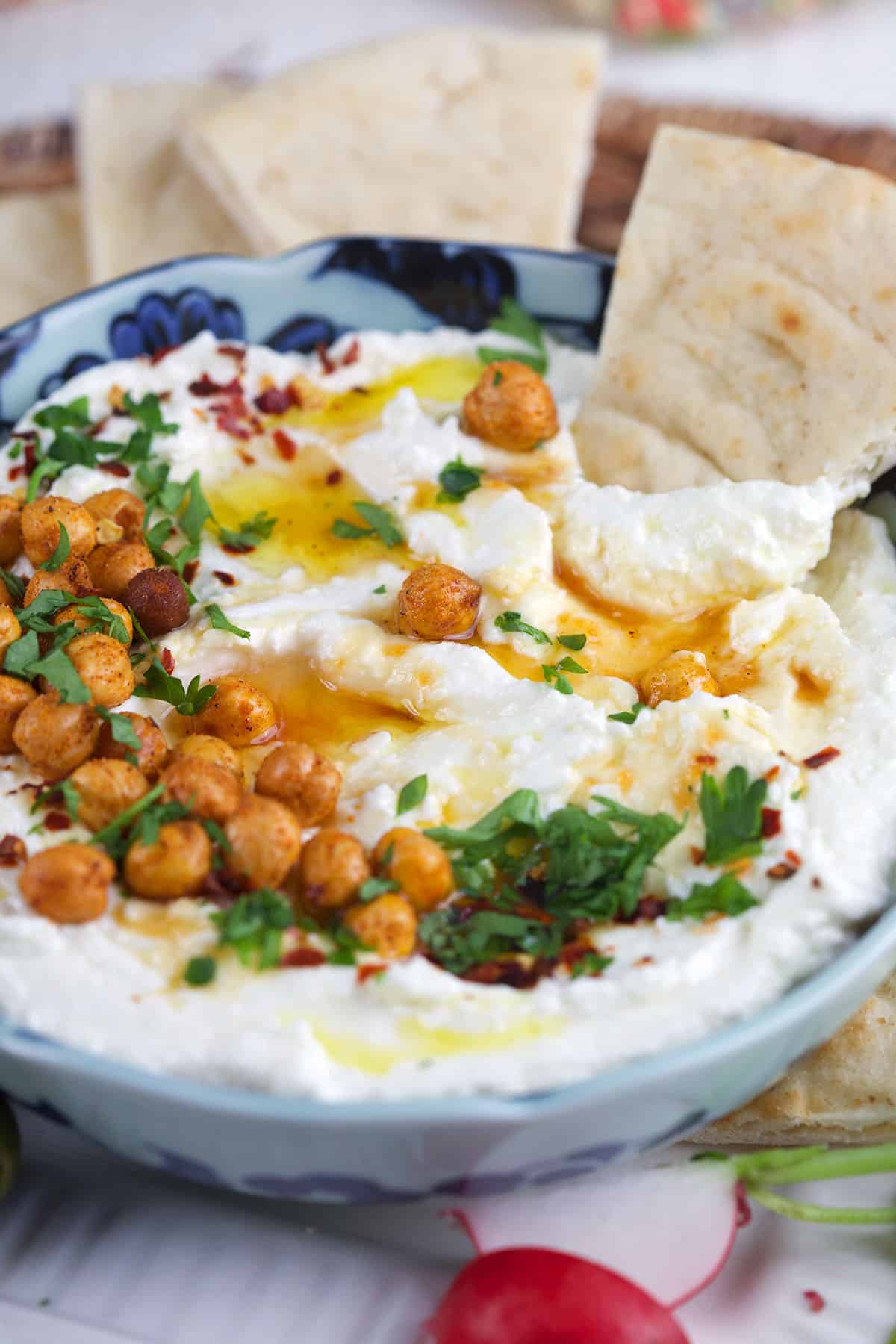 A piece of pita bread is being dipped into feta dip. 