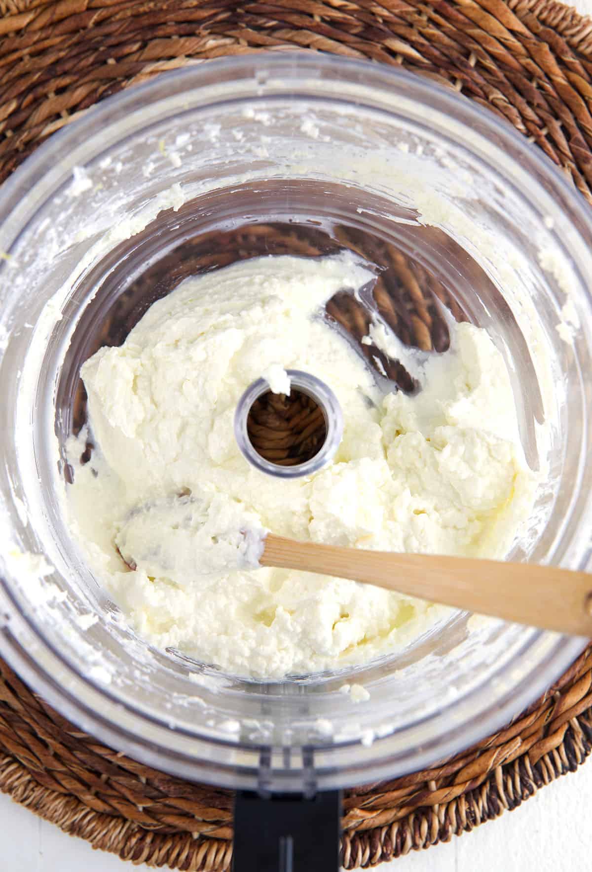A food processor contains a portion of whipped feta dip. 