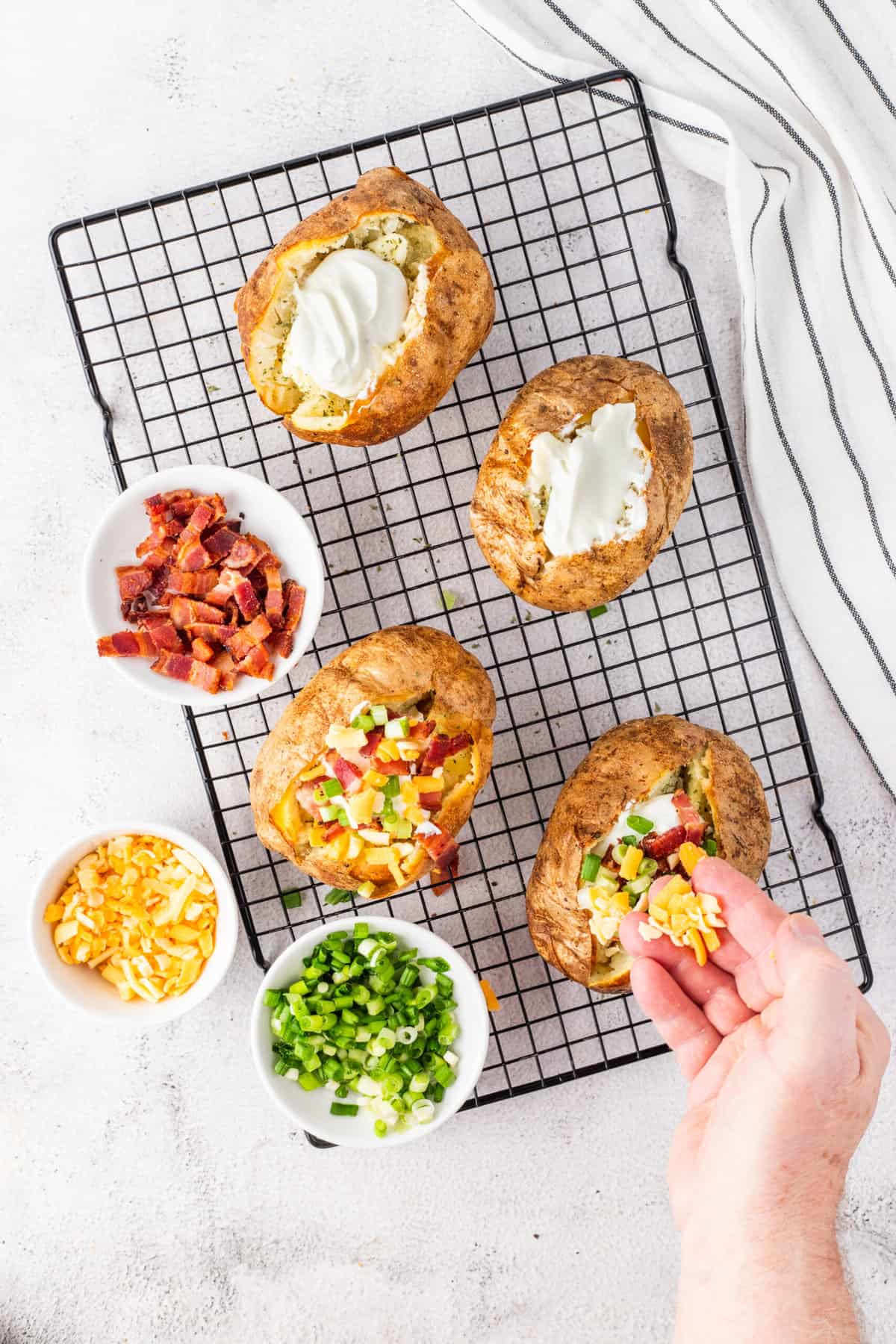 Toppings are being spread all across baked potatoes. 