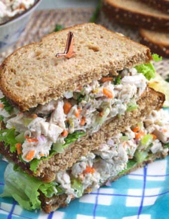 A halved chicken salad sandwich is placed on a plate.