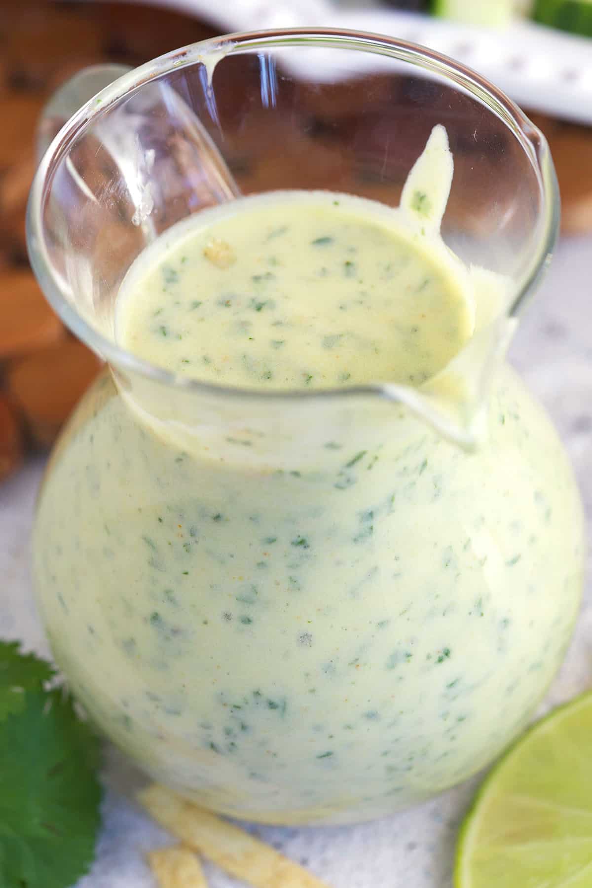 A small glass pitcher is filled with creamy dressing. 