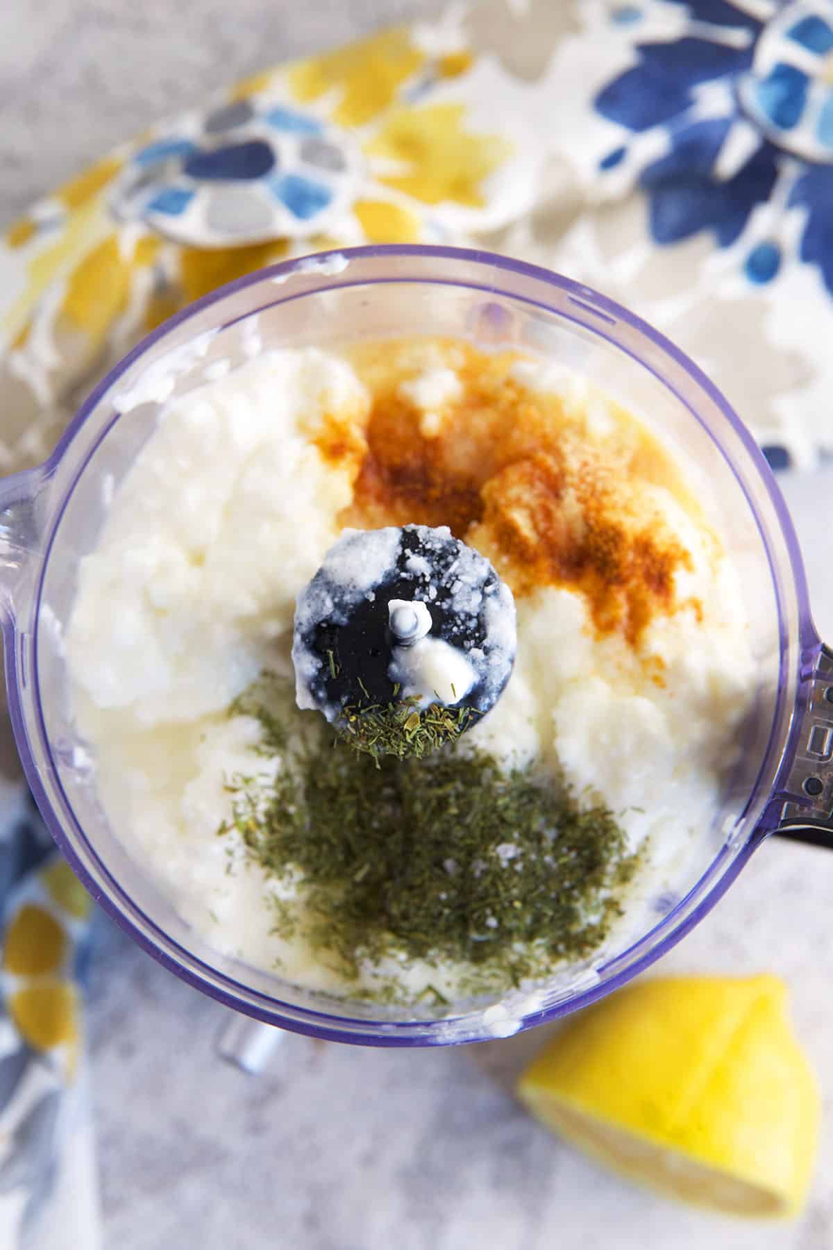 A food processor is filled with the ingredients for cottage cheese dip. 