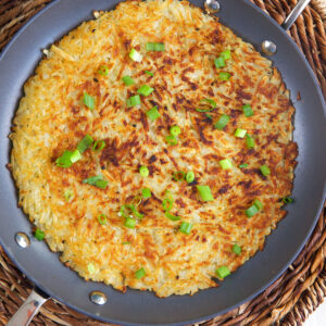 A skillet is filled with cooked hash browns.