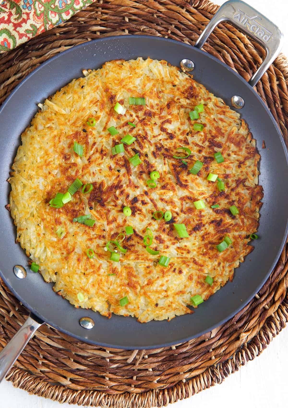 A skillet is filled with cooked hash browns. 